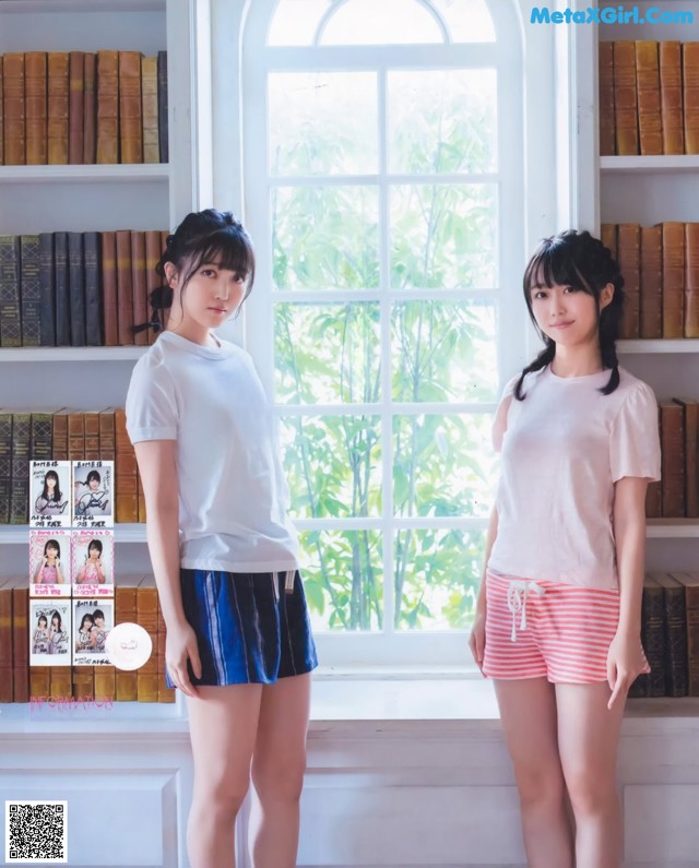 A couple of women standing next to each other in front of a window.