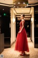 A woman in a red dress standing in a hallway.