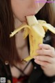 A woman is eating a banana with her mouth open.