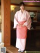 A woman in a pink kimono standing in a room.