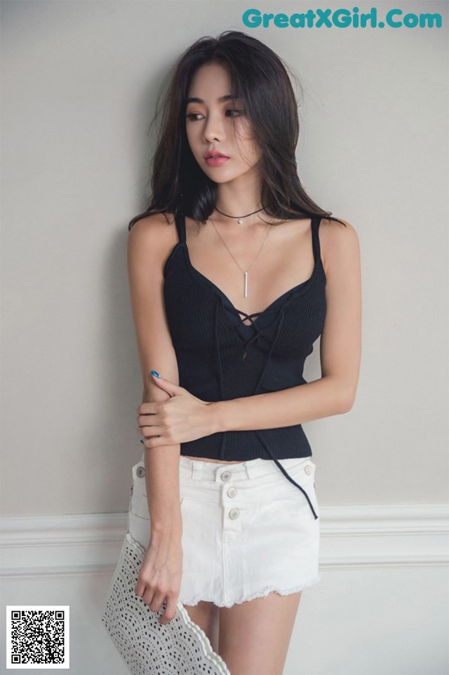 A woman in a black top and white shorts posing for a picture.