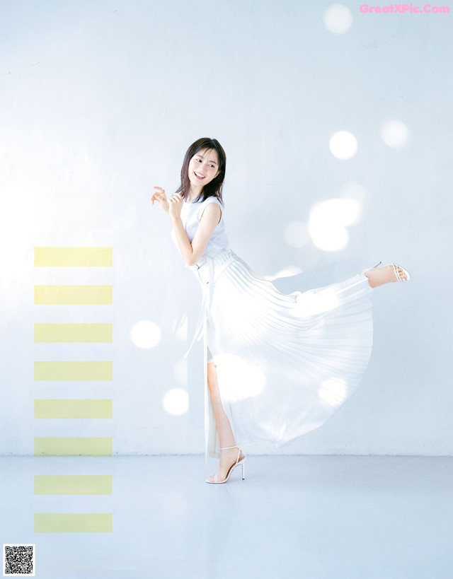 A woman in a white dress is posing for a magazine.