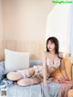 A woman sitting on a bed wearing a white lingerie.