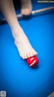 A person's foot on a pool table with a red ball.