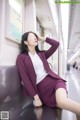 A woman in a purple suit sitting on a train.