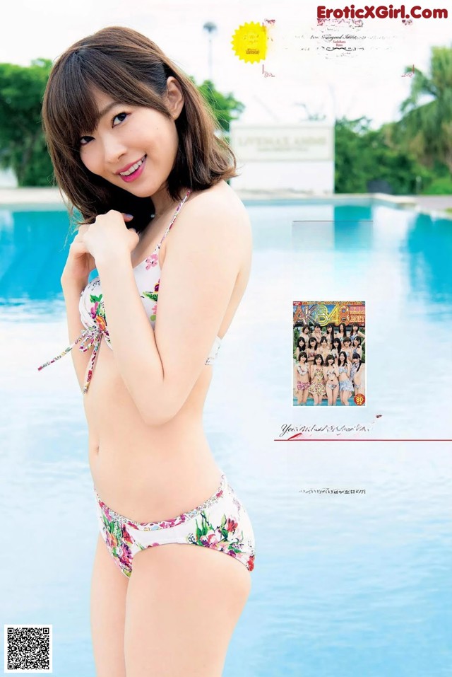 A woman in a bikini standing next to a swimming pool.