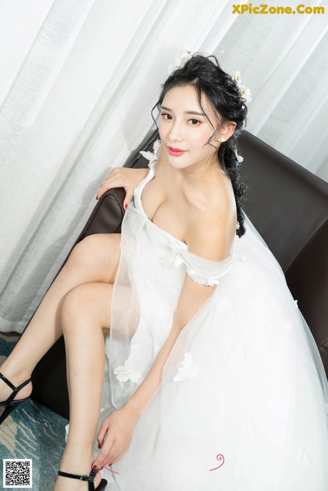 A woman in a wedding dress sitting on a couch.