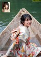 A woman in a kimono sitting in a boat on the water.