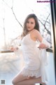 A woman in a white dress posing on a balcony.