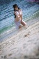 A woman in a white bikini standing in the water.