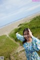 A woman in a blue and white dress standing on a beach.